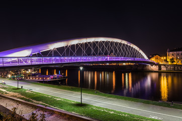 Fototapeta na wymiar Bernatka footbridge over Vistula river in Krakow in the night