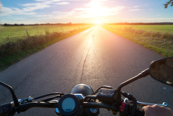 Motorradfahrer auf Landstrasse bei Sonnenuntergang