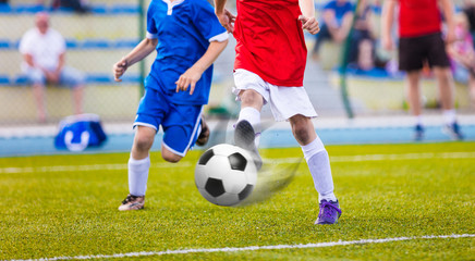 Obraz premium Youth soccer league.Training and football match between youth soccer teams. Running football players kicking ball.
