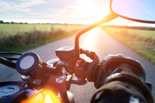 Fototapeta Motorrad fahren auf Landstrasse im Sonnenuntergang bei blauem Himmel