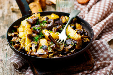 fried potato with mushrooms in a vintage frying pan