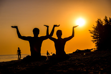 Fototapeta premium An attractive young woman and man doing yoga on the beach, Sea