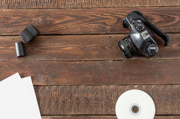 Camera, films, paper and cd on wood table