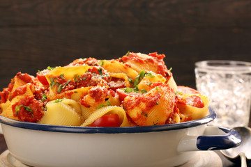 Lumaconi pasta with tomato sauce on wooden background