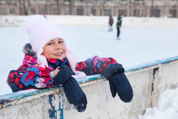 Tired and happy young girl after skating on the ice of open air icerink, winter season