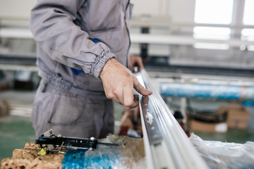 Factory for aluminum and PVC windows and doors production. Manual worker assembling PVC doors and windows. 