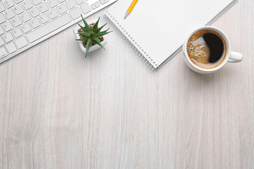 Cup of coffee with office tools on light wooden background