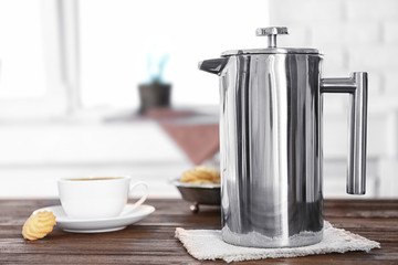 New coffee maker and cup of fresh drink with cookies on kitchen table