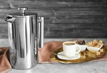New coffee maker and cup of fresh drink on wall background