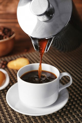 Fresh coffee pouring from pot into cup