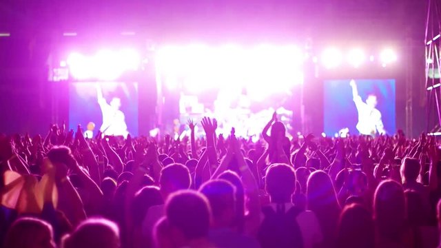 raised a lot of brightly lit hands at a concert, a large number of people, the audience on the background of the scene with bright colored lights, outdoor rock concert, outdoor concert