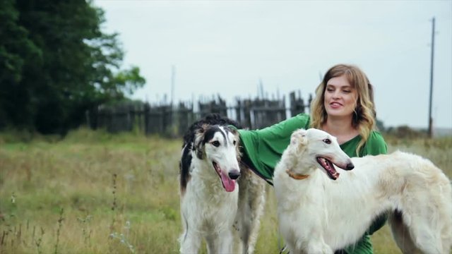 girl in green dress with two Russian greyhounds