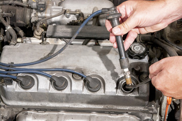 Mechanic tests a spark plug in an automobile
