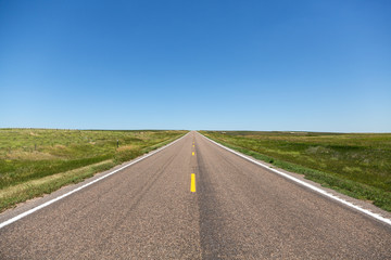 A road cutting through rolling hills in northern Nebraska on a summer day.