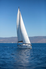 Yacht with white sails in the sea. Luxury boats.