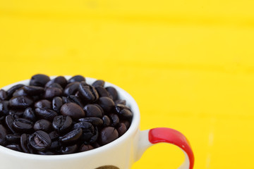 coffee bean in coffee cup with yellow background.