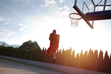 Young man jumping and making a fantastic slam dunk playing stree