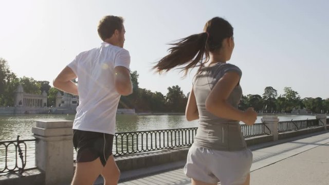 Runners jogging running in Madrid El Retiro city park. Exercising woman and man runner training on jog living healthy lifestyle in Buen Retiro Park, Parque el Retiro in Madrid, Spain, Europe.
