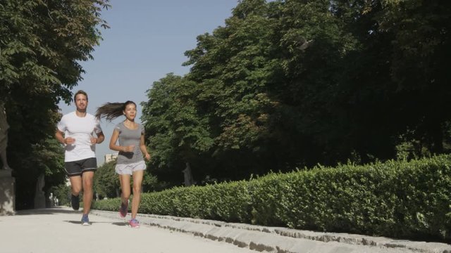 Runners running couple jogging in city park. Exercising woman and man runner training together on run living healthy active lifestyle in Buen Retiro Park, Parque el Retiro in Madrid, Spain, Europe.