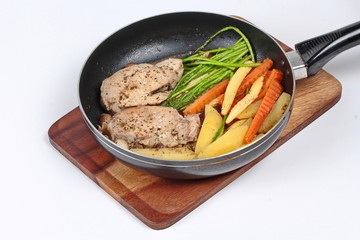 Home made ,Cooking pork steak with mixed vegetables in pan before served isolated on background.