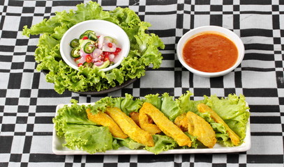 Pork satay served with Thai cucumber chili sauce and nut sauce on black - gray  tablecloth.