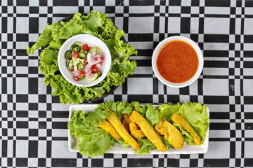 Pork satay served with Thai cucumber chili sauce and nut sauce on black - gray  tablecloth.