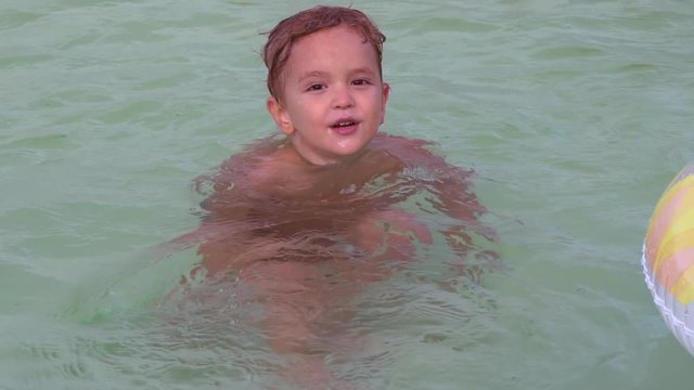 Portrait little boy swimming in the pool. Happy kid 4 years old enjoy summer playing and swim in the river or lake or sea. Smiling cute child play in the water.