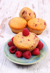 Fresh baked muffins with raspberries on old wooden background, delicious dessert
