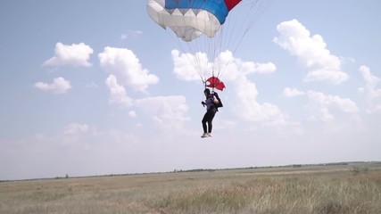 Parachutist hovering in the sky and lands. parachute as a Russian flag. parachutist landed on the field