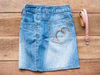 Skirt jean with pink belt on wood background
