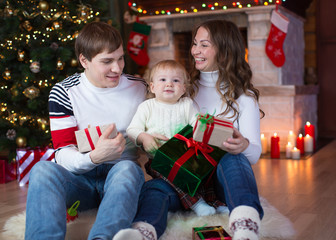 Family exchanging gifts in front of Christmas tree