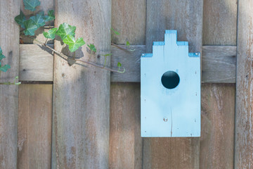 Blue birdhouse on a wooden fence