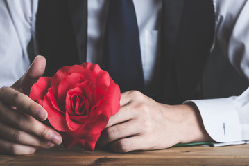 赤いバラの花を持っている男性