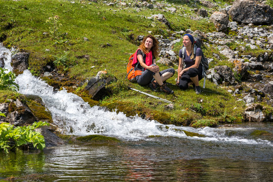 Female Hikers relaxing next to mountain river