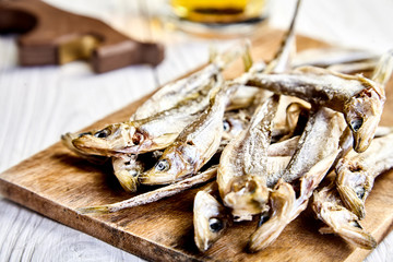Dried fish on chopping board, mug of beer behind