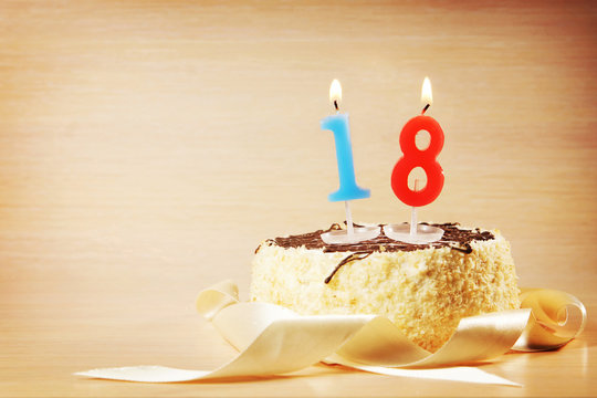 Birthday cake with burning candle as a number eighteen. Focus on the candle