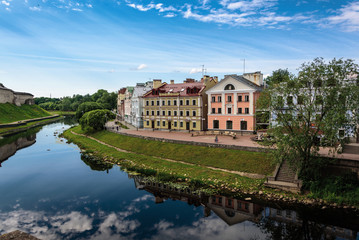 Fototapeta na wymiar View of the embankment from the bridge through the river of Pskov in summer sunny day
