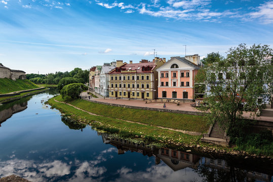 View of the embankment from the bridge through the river of Pskov in summer sunny day