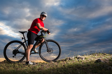 Obraz na płótnie Canvas Cyclist riding mountain bike on trail at evening.