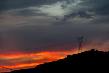 Anochecer rojo/ Anochecer con cielos rojos y azules sobre monta&ntilde;as y torres de alta tensi&oacute;n.