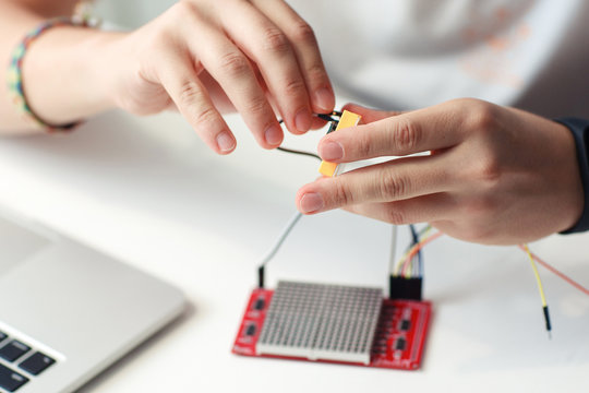 Engineer hands connecting electronic components. Close-up of master developing new device, blurred led matrix display