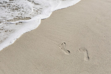 close up of footprints on the beach with golden sand