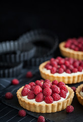 Delicious raspberry mini tarts on dark background