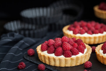 Delicious raspberry mini tarts on dark background