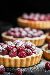 Delicious raspberry mini tarts on dark background