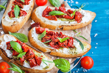Bruschetta with cream cheese, pesto, fresh basil and sun dried t