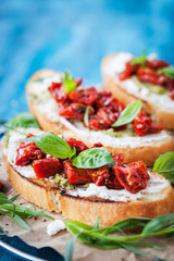 Bruschetta with cream cheese, pesto, fresh basil and sun dried t