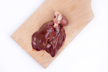 Raw chicken liver on the wooden cutting board over white backgro