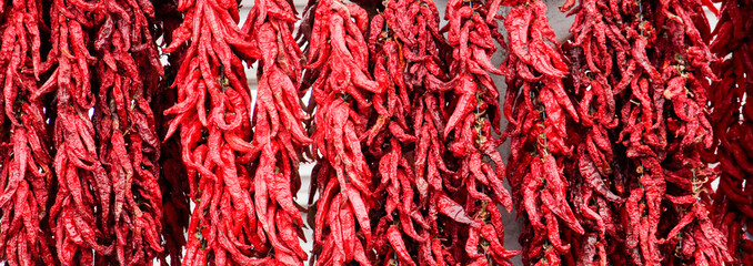 Fototapeta premium Red hot chili peppers hanging on a ropes on an open market for sale