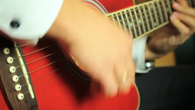 Guitarist playing on six-string acoustic guitar. Close up of hands and guitar strings.